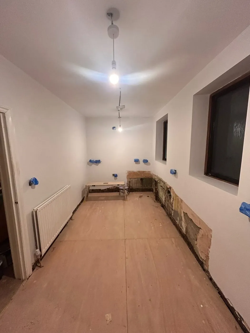 The same room after plastering: smooth white walls and ceiling ready for paint