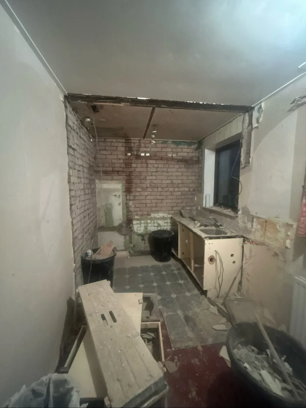 Room mid-renovation, stripped back to bare brick with old plaster removed